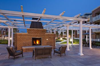 Outdoor fireplace with white pergola and seating
